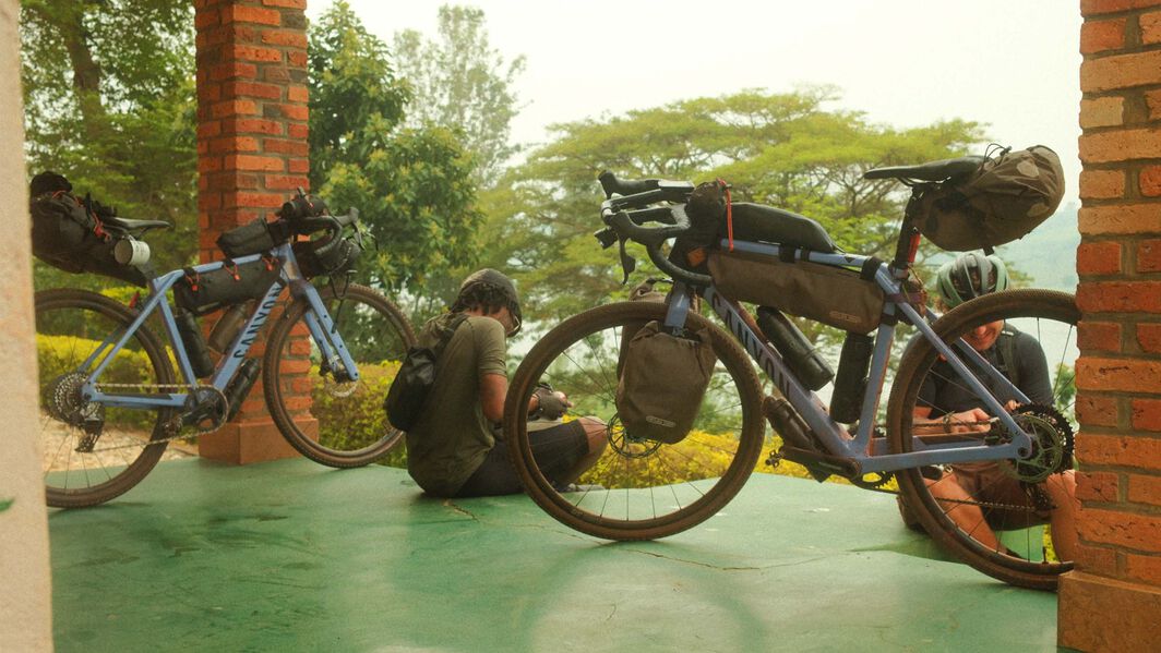 Two Canyon gravel bikes equipped with full bikepacking setups, including frame bags, handlebar packs, and saddle bags, resting while riders prepare for the next leg of their journey.